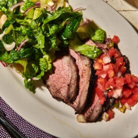 Sliced Santa Maria grilled tri-tip steak on plate with salsa and salad.