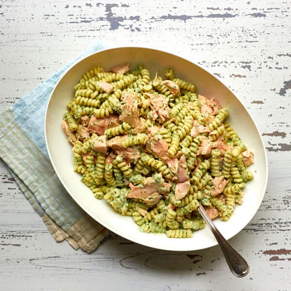 Serving bowl with salmon pasta salad in creamy cilantro dressing and spoon.