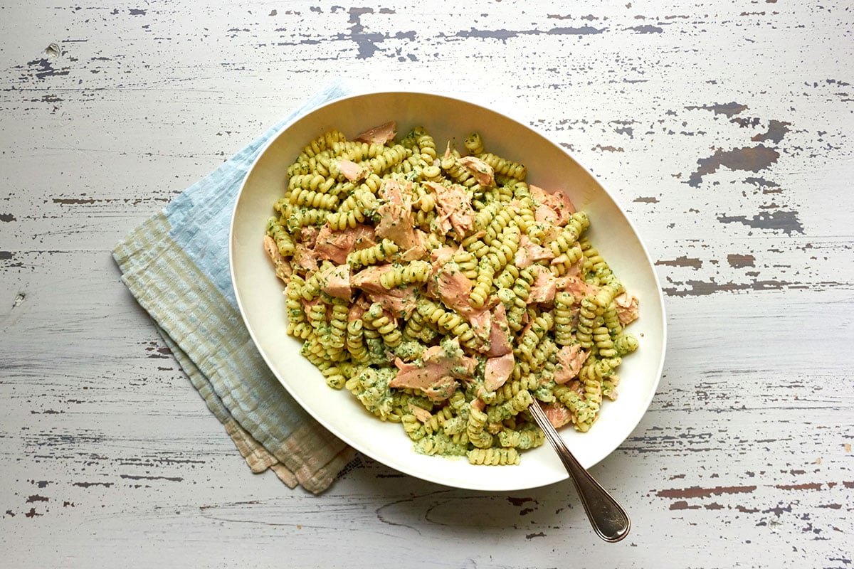Serving bowl with salmon pasta salad in creamy cilantro dressing and spoon.
