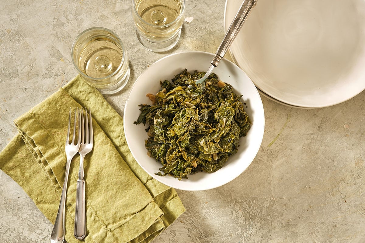 Table setting with bowl of Southern-style mustard greens.