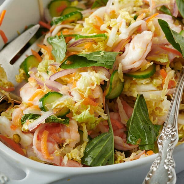 Vietnamese-style cabbage salad in white serving dish with spoons.