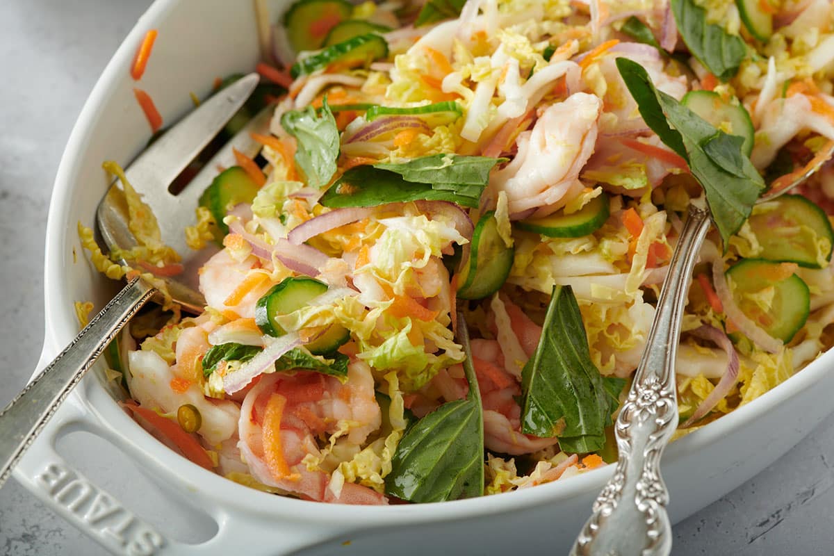 Vietnamese-style cabbage salad in white serving dish with spoons.