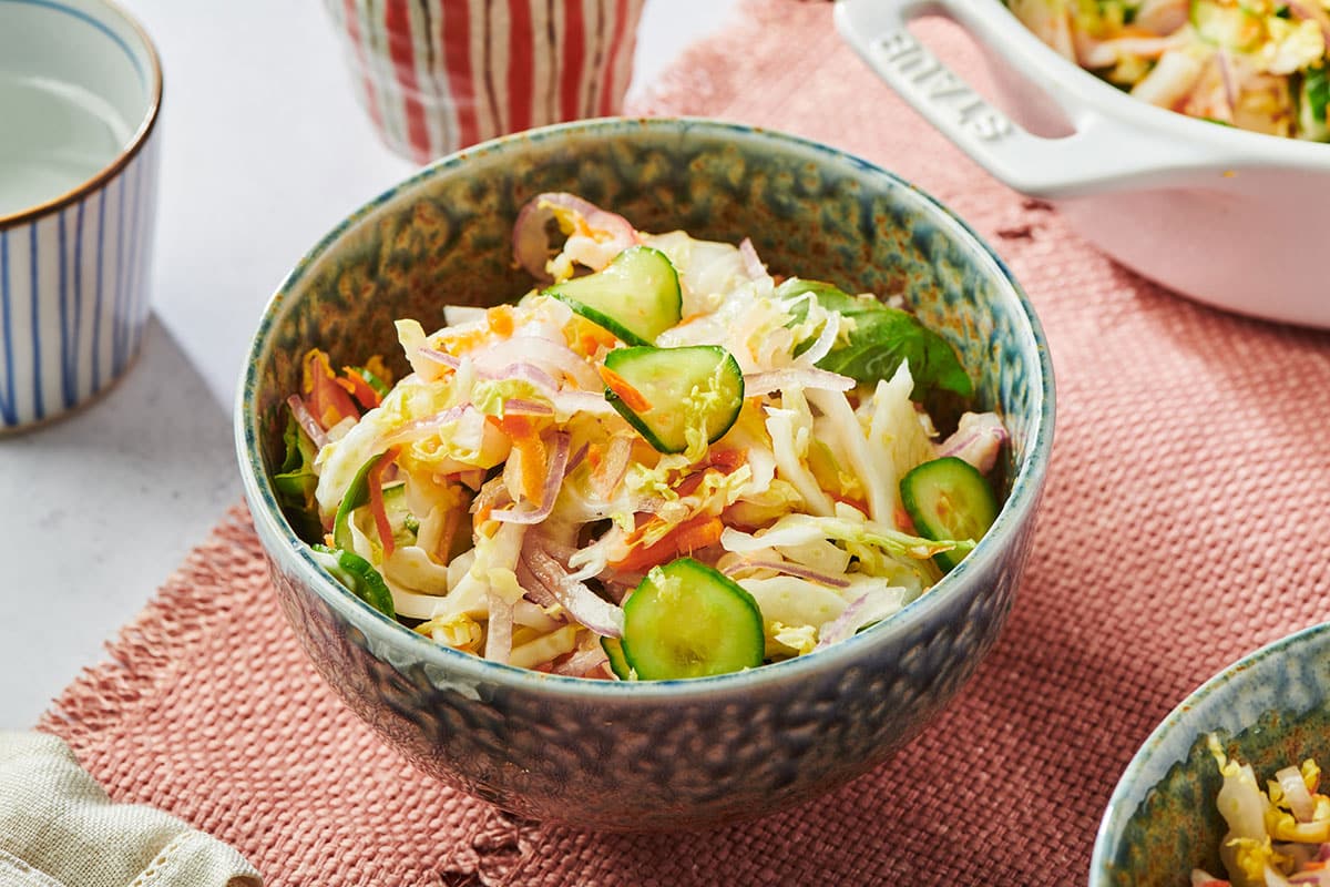 Grey bowl with cabbage salad on table with other dishes.