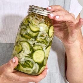Woman holding jar of refrigerator pickles.
