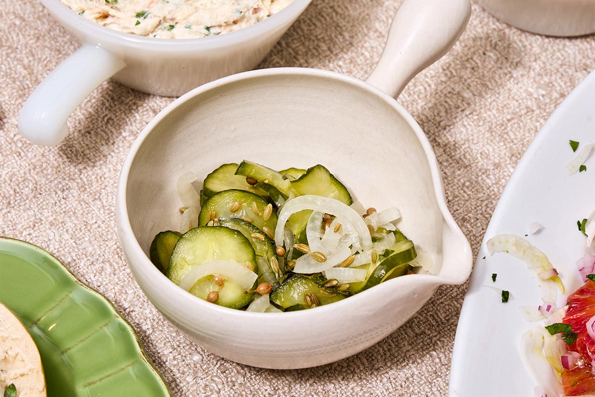 Sliced refrigerator pickles in white bowl on table.