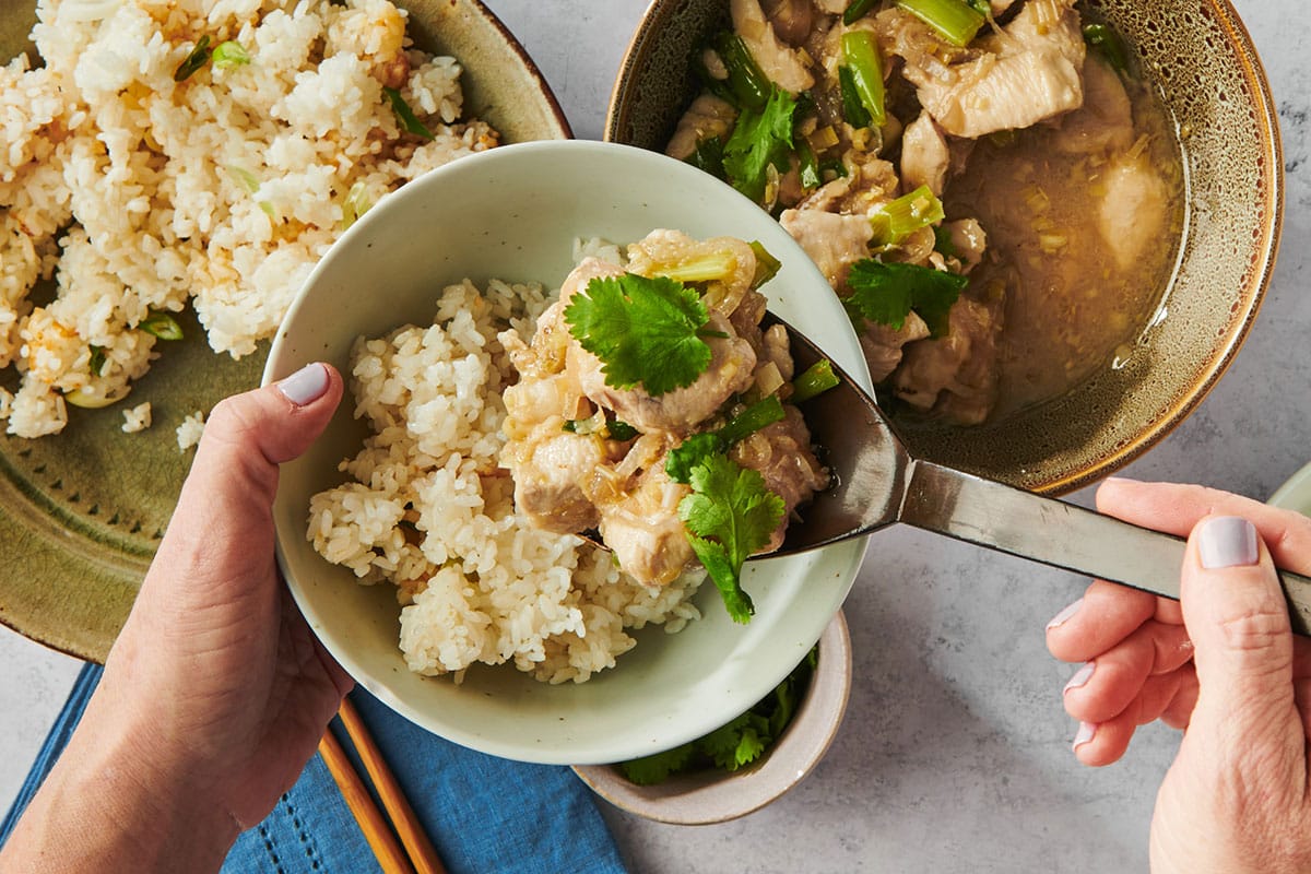 Serving stir-fried chicken with lemongrass over rice in bowls.