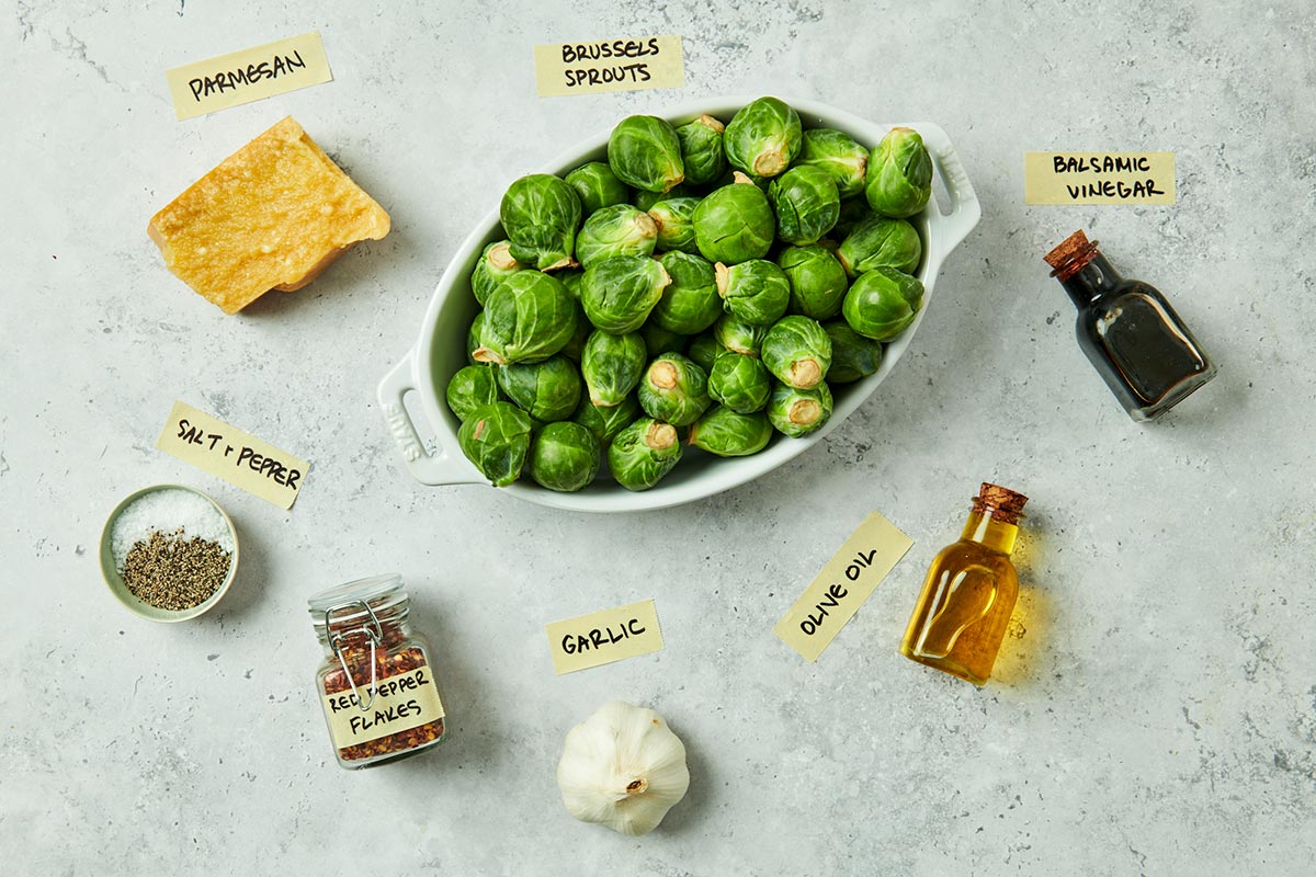 Parmesan cheese, Brussels sprouts, and other ingredients on marble table.