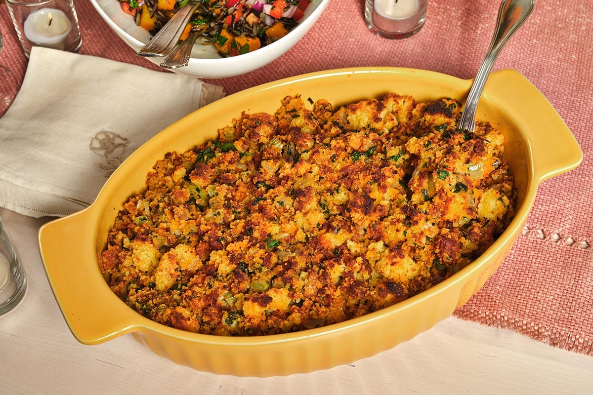 Yellow bowl filled with chorizo and cornbread stuffing on table.