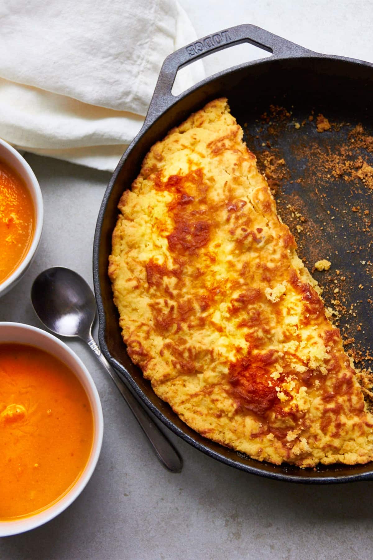 Cheddar Cornbread in pan next to tomato soup in bowls.