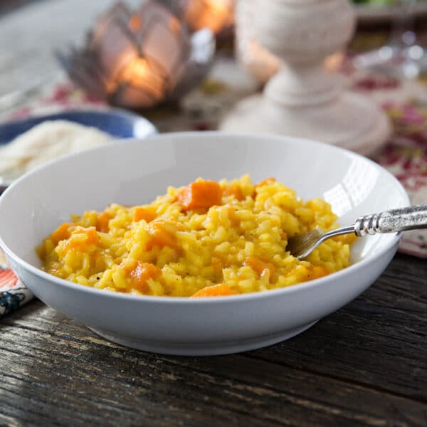 Butternut squash risotto in small bowl on table with spoon.