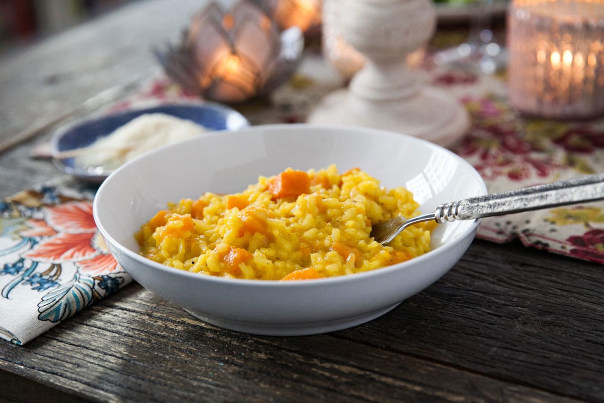 Butternut squash risotto in small bowl on table with spoon.