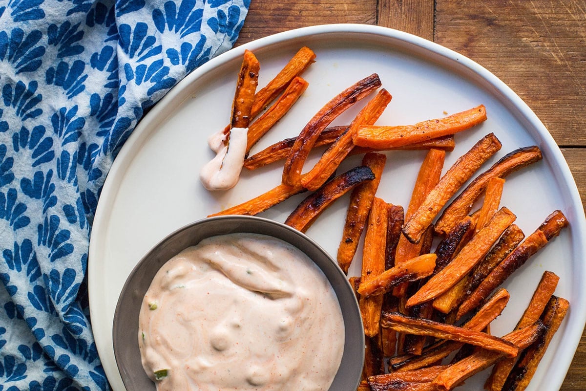 Carrot Fries on plate with bowl of Sriracha Sauce.