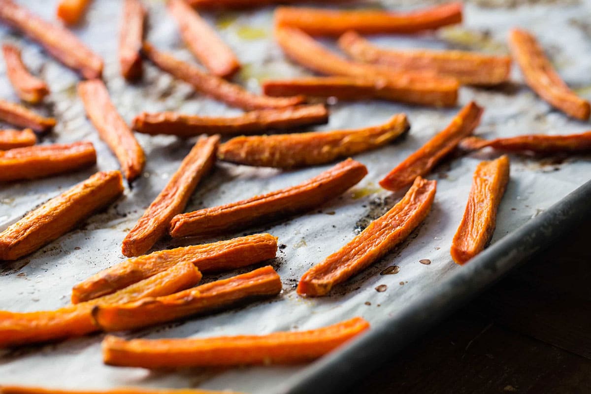 Carrot fries on parchment-lined baking sheet.