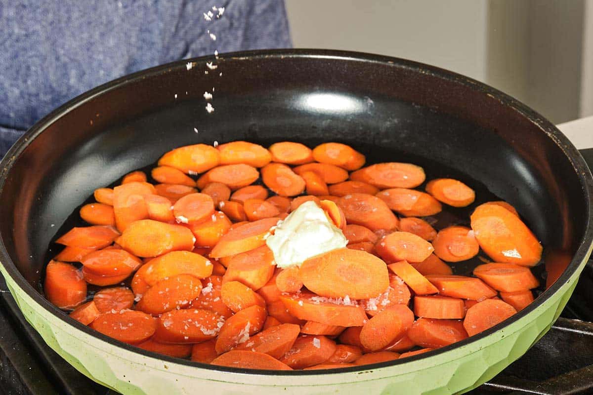 Sliced carrots in skillet with butter and salt.
