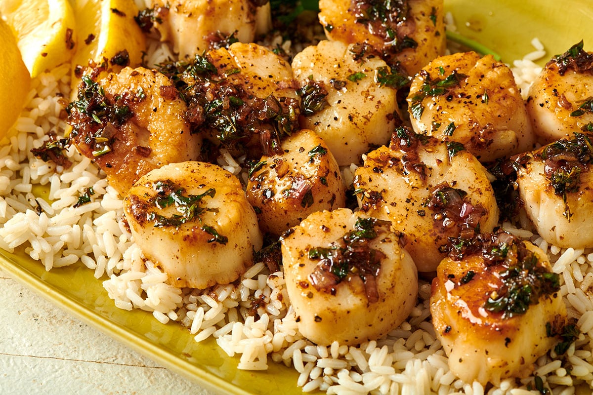 Yellow plate with lemon butter sea scallops over rice.