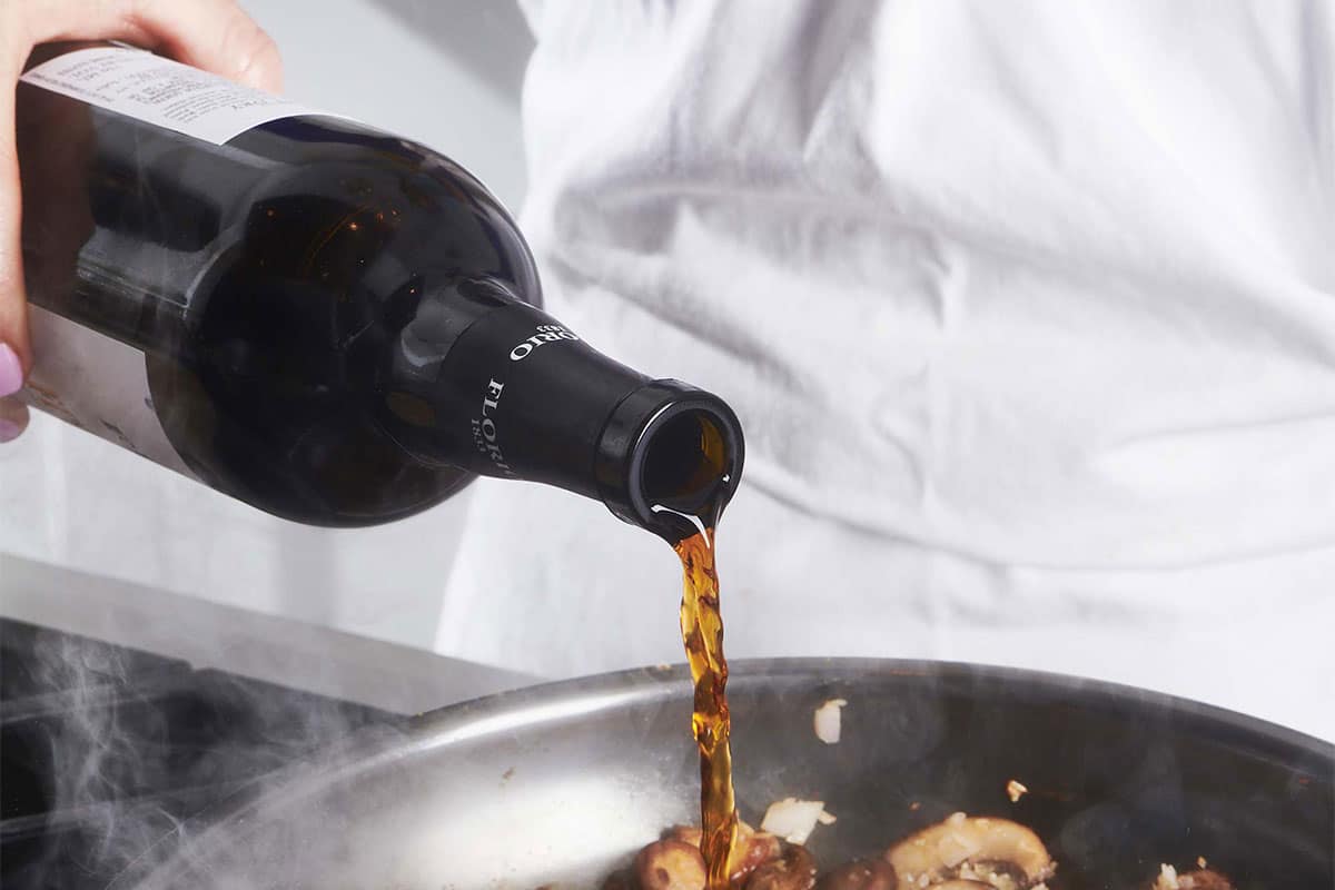 Pouring Marsala wine into pan of food.