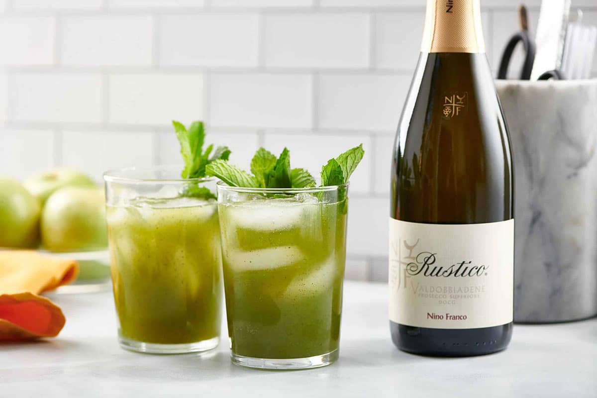 Two green Vodka Prosecco Cocktails in small glasses on table with bottle of Prosecco wine.