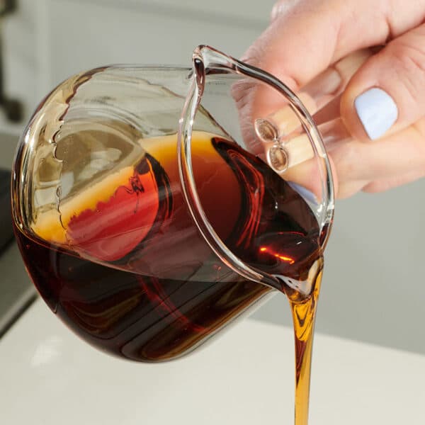 Woman pouring maple syrup from glass jar.