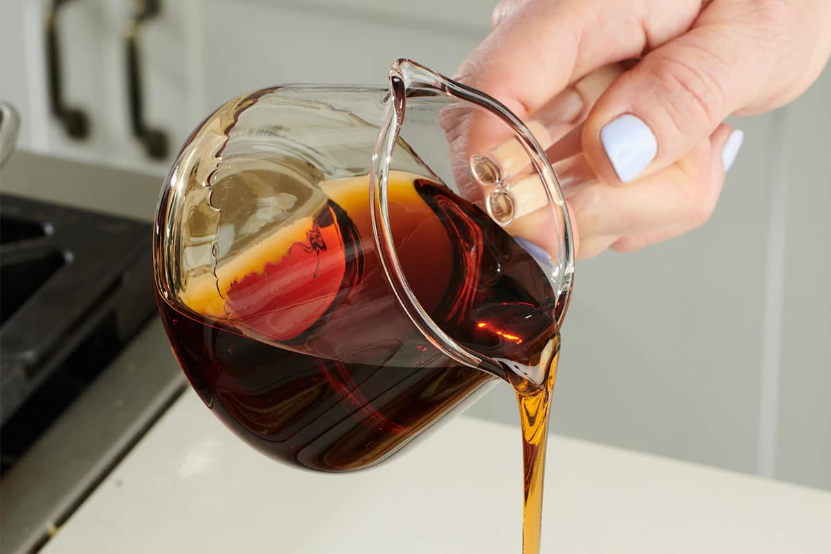 Woman pouring maple syrup from glass jar.