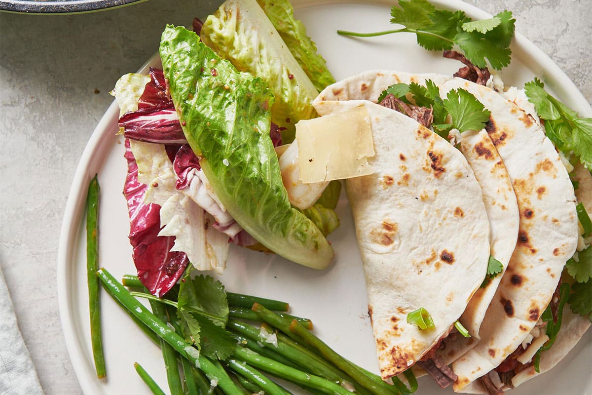 Salad with Mustard Vinaigrette on a plate with beans and tacos.