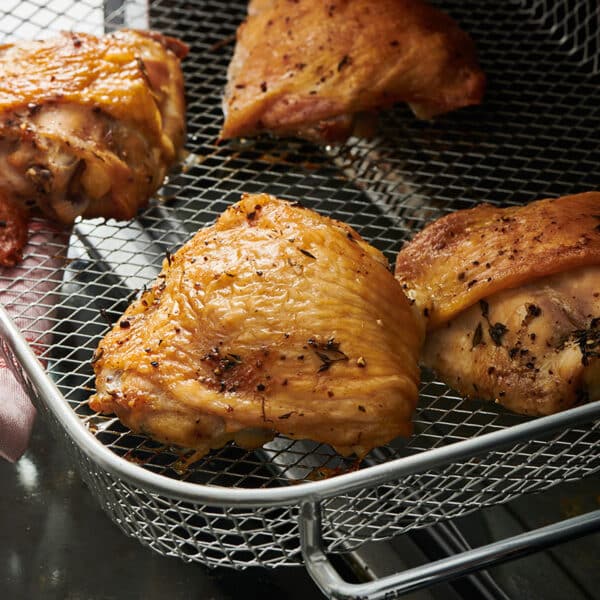 Katie Workman pulling pan of chicken thighs out of air fryer.