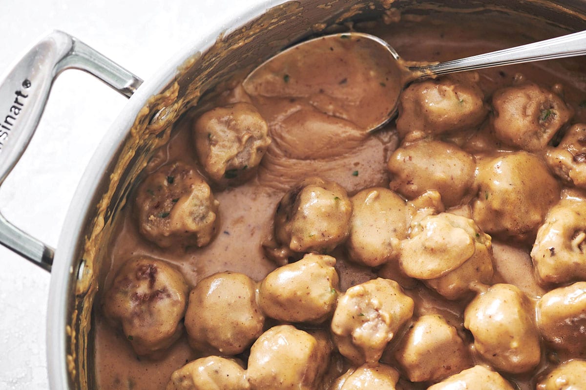 Spoon in a pan of Swedish Meatballs.