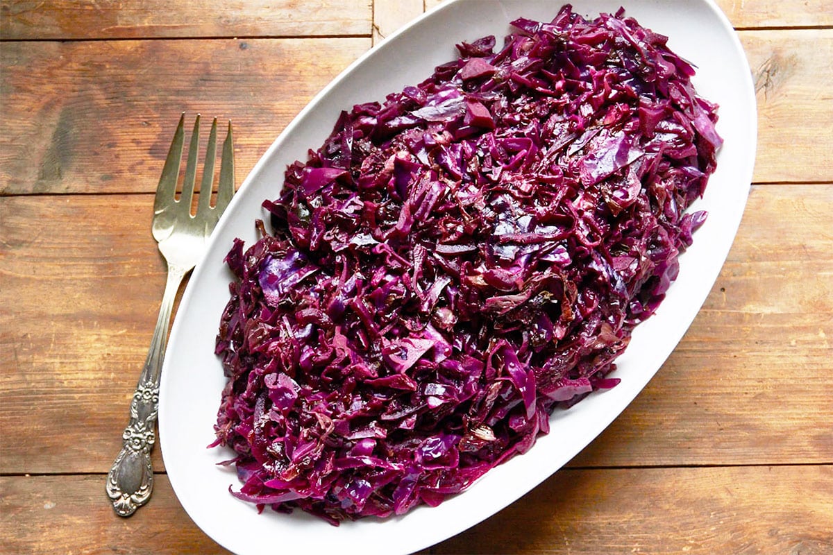 Braised red cabbage in large white serving dish on table.