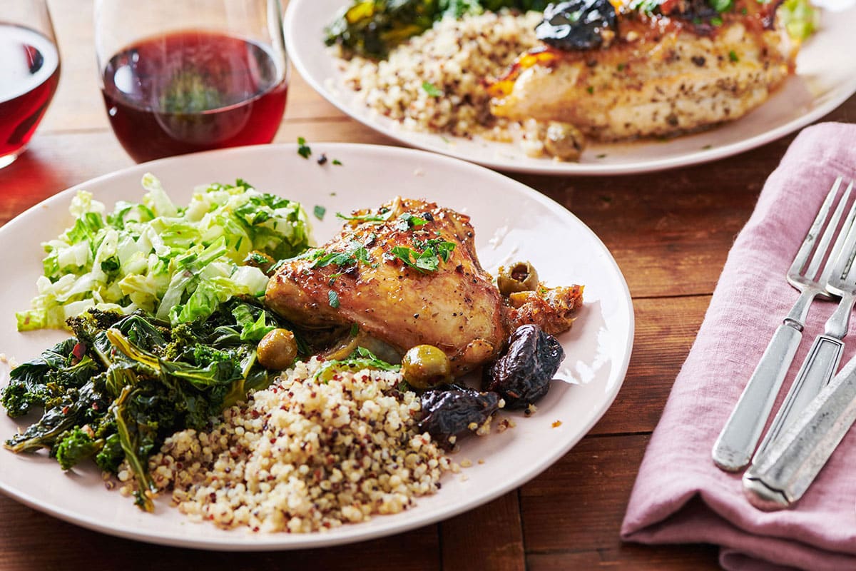Chicken Marbella on white plate with side dishes.