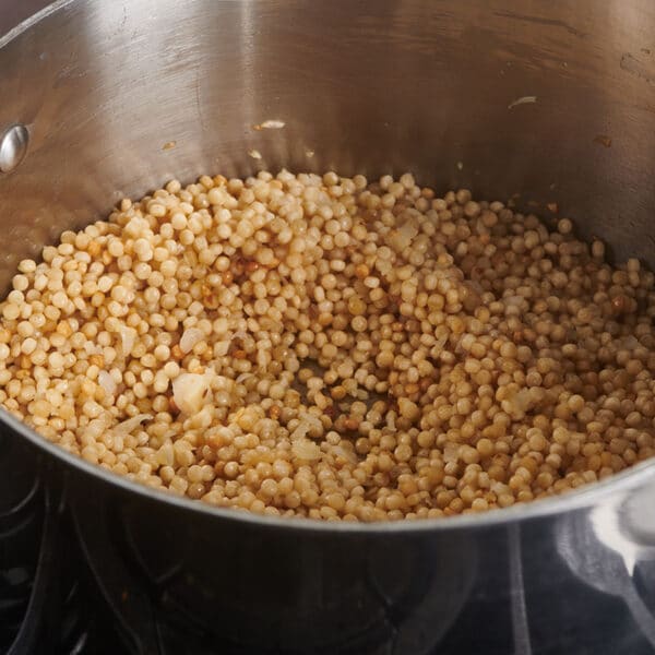 Cooking Israeli couscous in saucepan on the stove.
